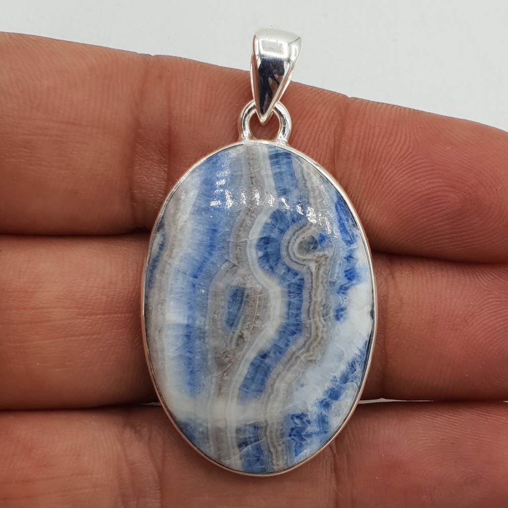 A silver pendant set with an oval cabochon Scheeliet