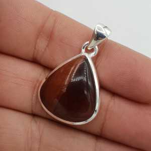 A silver pendant set with large teardrop shaped red tiger's eye