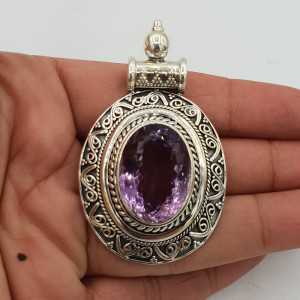 A silver pendant with a faceted Amethyst, set in a carved setting